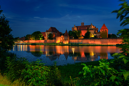 Malbork, Poland - August 13, 2023: The Castle of the Teutonic Order in Malbork by the Nogat river at dusk. Poland