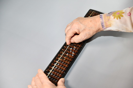 Fingertips of a senior woman operating an abacus