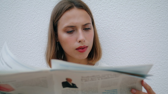 Relaxed girl reading newspaper in morning closeup. Smiling woman looking camera