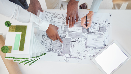 Top view, teamwork and architects hands on blueprint, model or building, architecture or construction project. Team, engineers and group planning development project, design sketch and tablet mockup