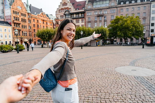 Girlfriend leading her boyfriend by the hand on the Stortorget Square in Malmo in Sweden.