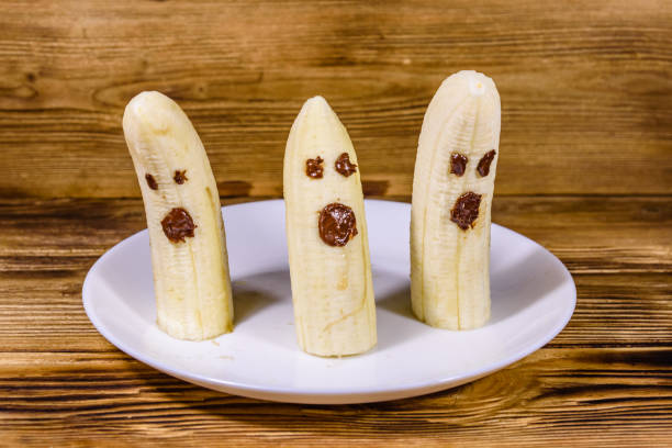 istock Scary banana ghosts in ceramic plate on a wooden table. Halloween concept 1798569201