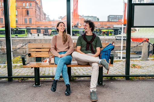 Young couple waiting for a bus at the bus stop in Malmo in Sweden.