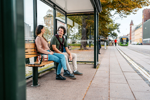 Young couple waiting for a bus at the bus stop in Malmo in Sweden.