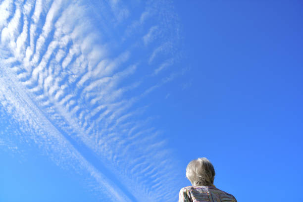 Senior woman looking at contrails in the blue sky