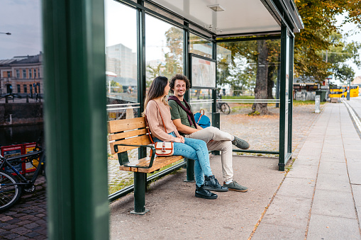 Young couple waiting for a bus at the bus stop in Malmo in Sweden.