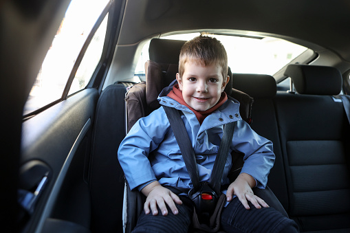 Boy sitting in a car seat for kids. About 5 years old, Caucasian male.