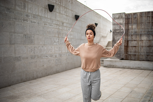 Healthy young woman skipping rope outdoors
