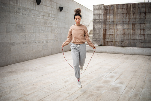 Healthy young woman skipping rope outdoors