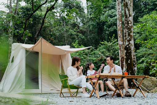 Asian Chinese parents with young daughter  having fun time glamping in the forest.