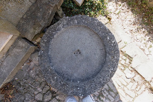 Top view of an old stone washbasin over a cobblestone floor during the day