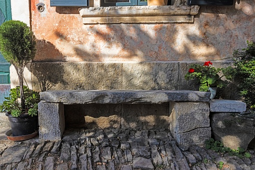 Image of a stone bench in front of an old building in a historic kraot village during the day