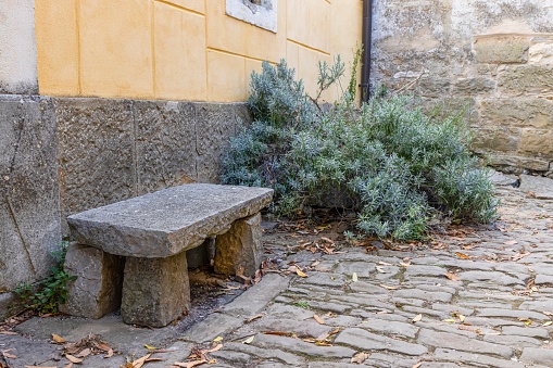 Image of a stone bench in front of an old building in a historic kraot village during the day