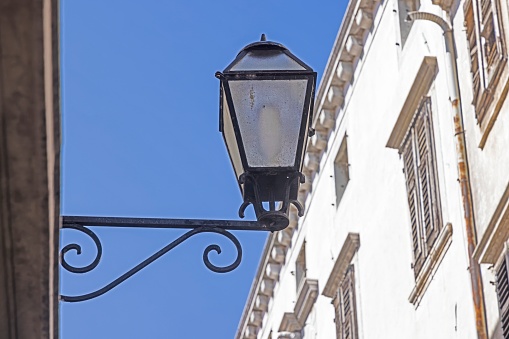 Picture of a historic street lamp on a house wall during the day