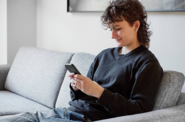 istock Side view of woman in couch using smartphone 1798619269
