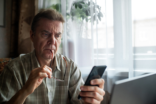 Senior man looking seriously at smartphone