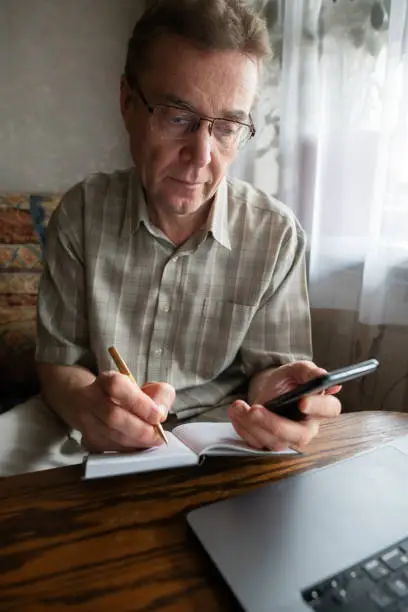 Photo of Senior man writing down verification code to protect himself from fraud.