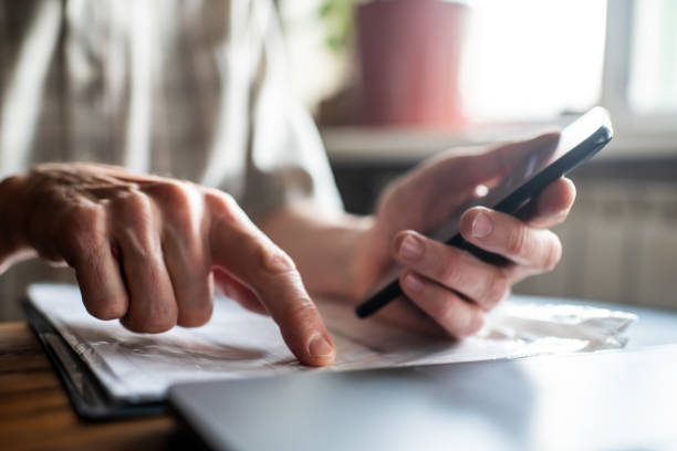 istock Senior man with smartphone  examining  bills, documents or receipts at home 1798631673