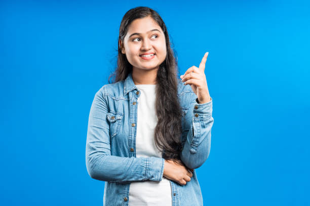 istock Smiling young Indian girl pointing finger upwards 1798631713