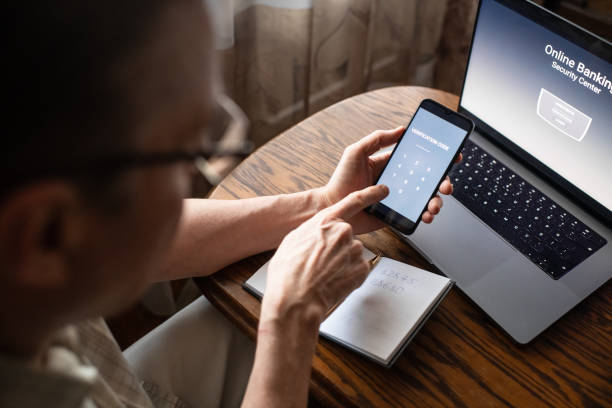 serious senior man at home entering verification code in smartphone, fraud prevention concept. - achterdocht fotos stockfoto's en -beelden