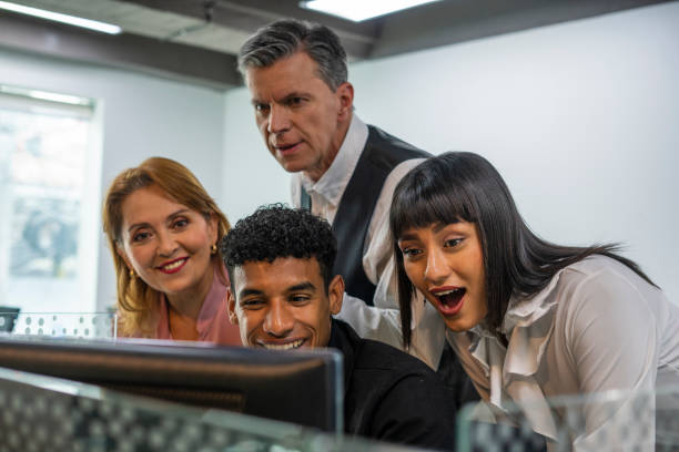 work group gathered in front of the computer, reviewing the weekly report, elegantly dressed