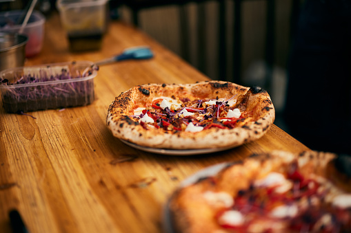 A pizza maker preparing and serving pizzas on the wooden table.