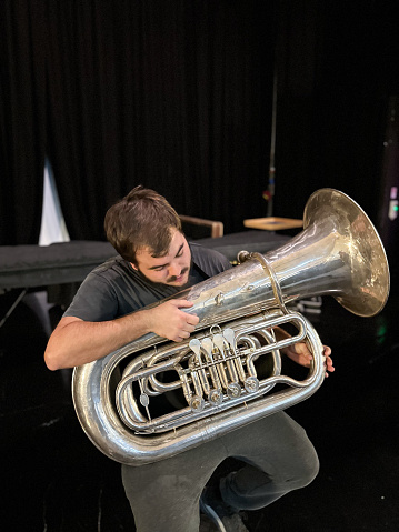 Man preparing to play a tuba backstage in a theater