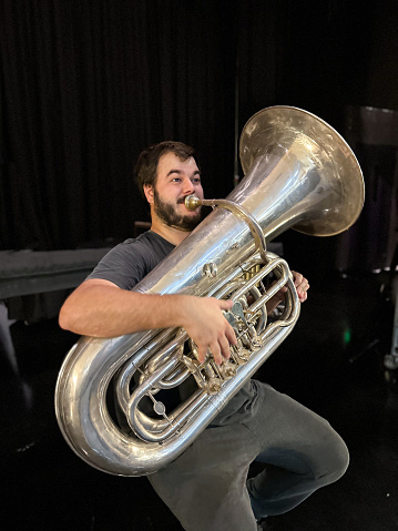 Man making faces while playing a tuba backstage in a theater