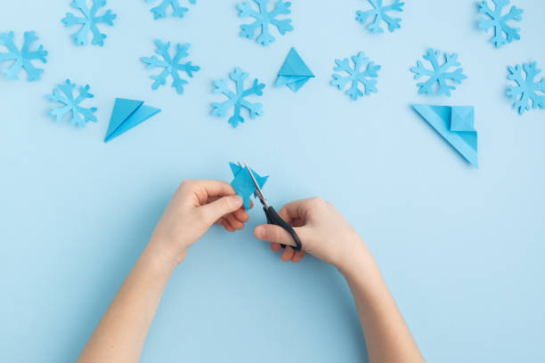 istock Hands making paper snowflakes on blue child hands 1798655046