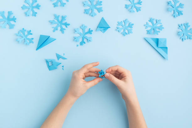 istock Hands making paper snowflakes on blue child hands 1798655619