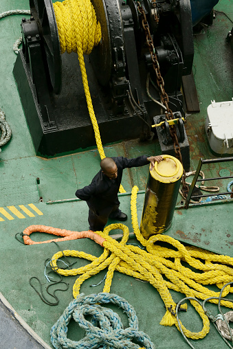 A deckhand secures a ship's mooring line, showcasing the essential skills and strength needed for maritime operations