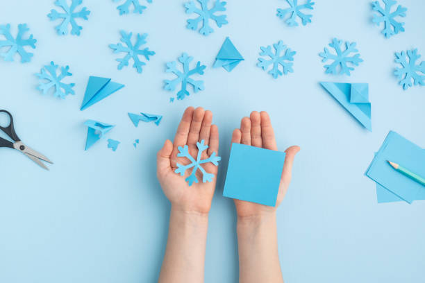istock Hands making paper snowflakes on blue child hands 1798658357