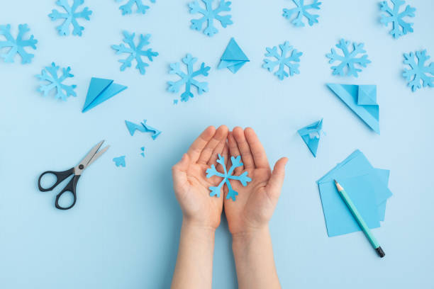 istock Hands making paper snowflakes on blue child hands 1798659445