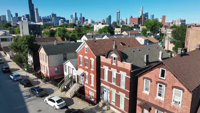 Chicago residential street with traditional brick houses and city skyline in the background. Aerial reveal on bright summer day.