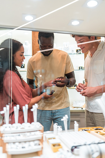 A diverse couple receiving a personalized in-store consultation from a helpful Caucasian seller while exploring jewelry options.