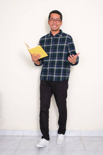 istock Full body portrait of a man smiling while holding a book 1798681164