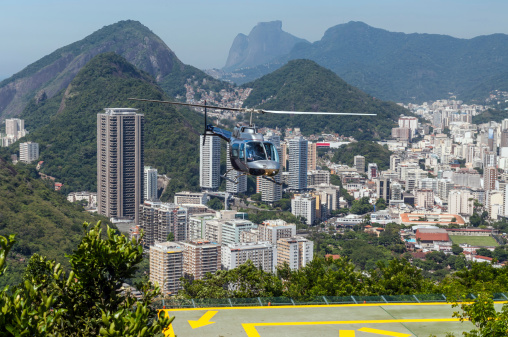 View of Rio de Janeiro. Helipad and Helicopter in the foreground. Tours of Rio de Janeiro are given atop Sugar Loaf Mountain by these helicopters. It was a hot, hazy tropical day. The helicoptar is coming in for a landing on the heliport on Sugar Loaf Mountain.