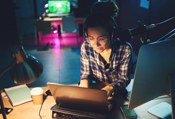 Live streaming, computer and podcast woman typing news article, broadcast report or planning platform strategy at night. Journalist or person on laptop and microphone for student politics or radio