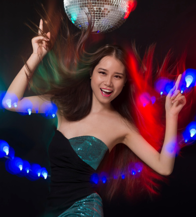 Vertical portrait of a cheerful young lady dancing under the music in the club