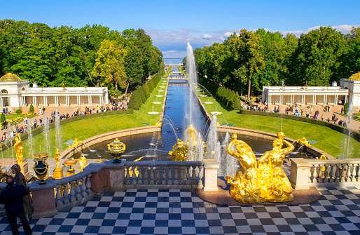 Saint-Petersburg - Russia October 4, 2022: Petergof. Grand Palace, fountains with bronze statues and many tourists in the lower park of Peterhof on a bright sunny day. Baltic Sea.