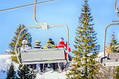 Skiers on a chairlift at a mountain resort on a sunny winter day
