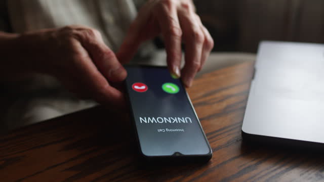 Senior man  answers a call from unknown number. Scam and fraud prevention with smartphone concept.