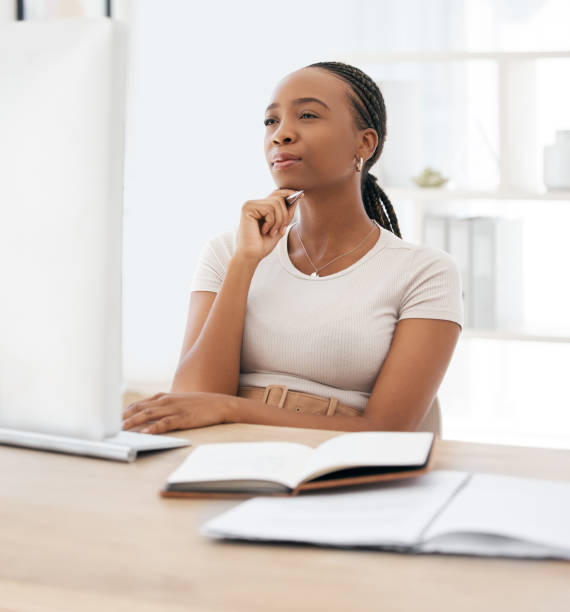 istock Thinking, research and notebook with black woman at computer for planning, goals and learning. Internet, technology and website with employee at desk  in office for idea, innovation and strategy news 1798781653
