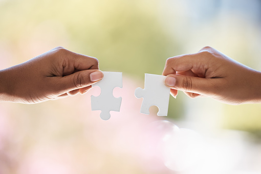 Group of business people holding a jigsaw puzzle pieces. Business solution integration concept. Multi ethnic group. Close up of hands