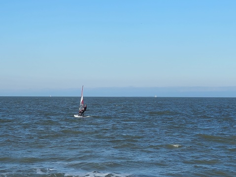 Individual on kiteboard surfing near Texas City Dike in Texas City, Texas. When the tide is right and the wind is welcoming, individuals flock to Texas City to enjoy kiteboarding. There is a strong kiteboarding culture in this area of Galveston Bay.