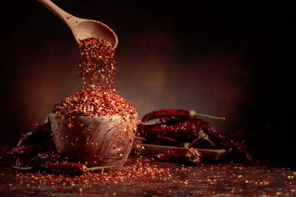 Photo of Chilli flakes are poured into a wooden dish.