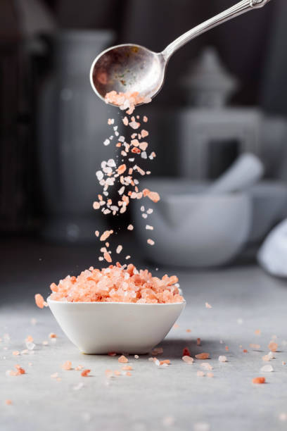 istock Pink salt in crystals is poured into a small white bowl. 1798848863