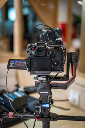 videography and photography equipment - top view flat lay of modern dslr camera, lenses, filters, microphone with windscreen, led light, memory cards and clapper board over white table background