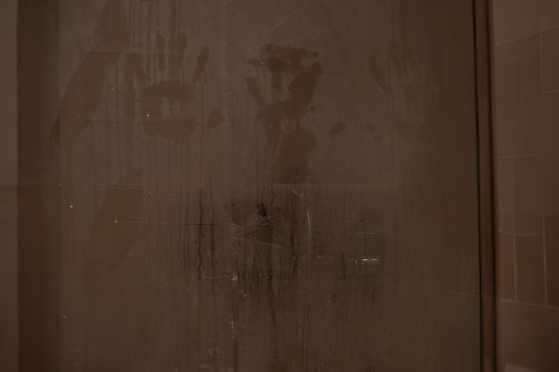 hand marks on a shower screen wet and fogged by the steam of hot water.