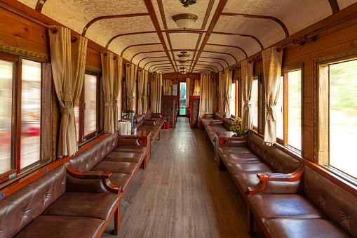 Interior of vintage old train carriage with leather chair, wooden floor, yellow curtains